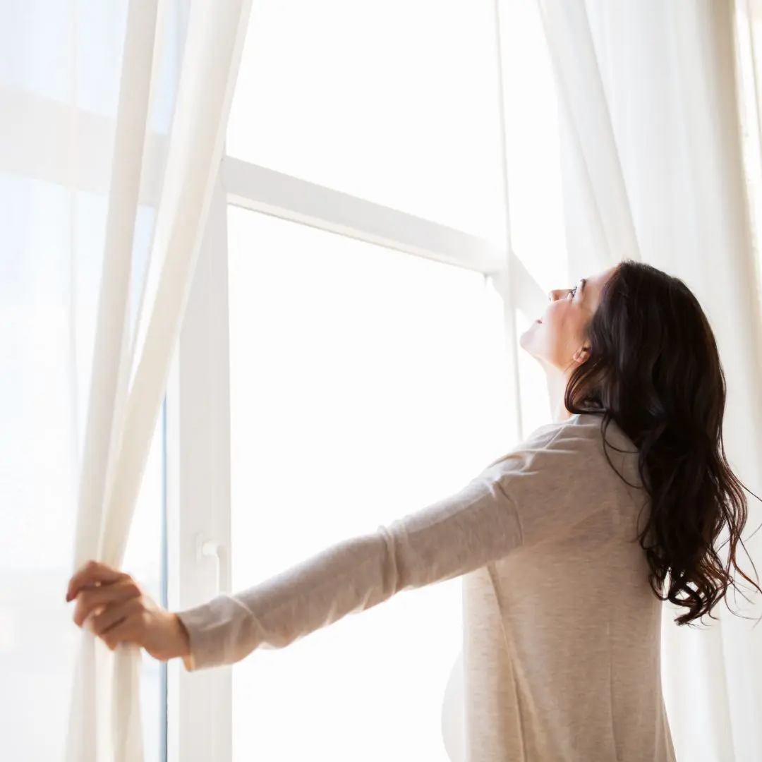 Woman Opening Curtains At Large Window