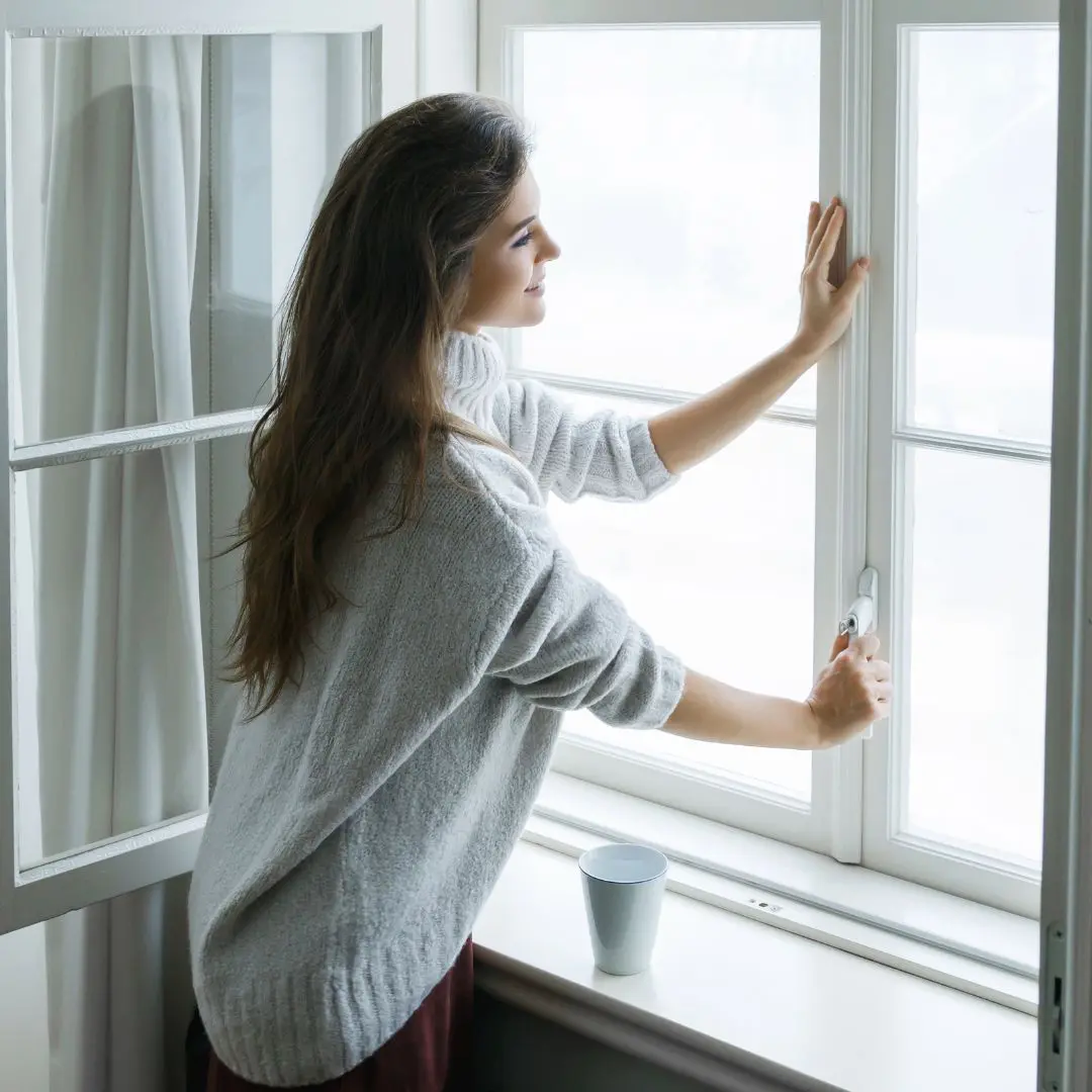 Woman Opening Window In Bright Room
